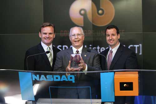 Collectors Universe CEO Michael R. Haynes (center), flanked by NASDAQ Stock Market executives Bruce Aust and Michael Beaver, holds a NASDAQ crystal commemorative plaque after the bell-ringing opening ceremony in New York City, July 22, 2005. Photo copyright 2005, The NASDAQ Stock Market, Inc. Reprinted with permission.