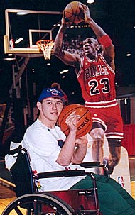 A young man in front of a cut-out of Michael Jordan on the court.