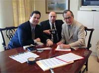 Michael 'Miles' Standish (left) of PCGS and Les Fox of West Highland Publishing (center) witness former President George Bush (right) in Houston adding his signature to the PCGS Autographed Coin Program